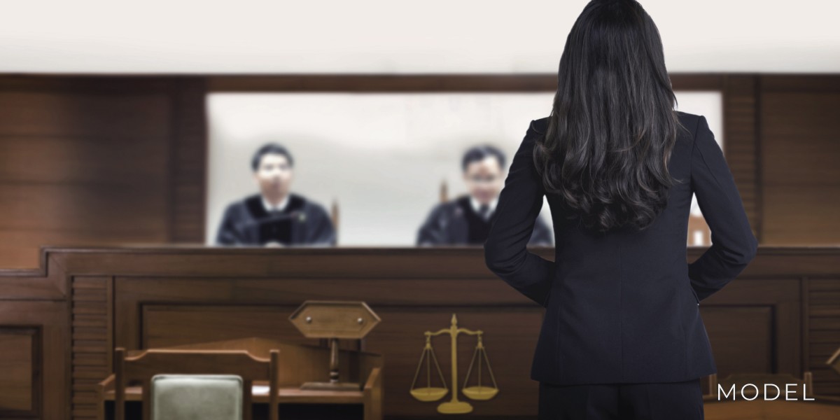 Women with black hair in front of judges as an forensic pathology expert witness.